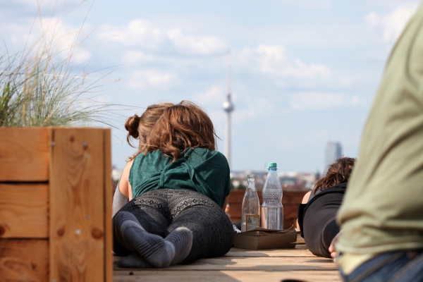 Junge Frau mit Getränken auf einer Dachterrasse mit Blick auf Berliner Fernsehturm, über dts Nachrichtenagentur